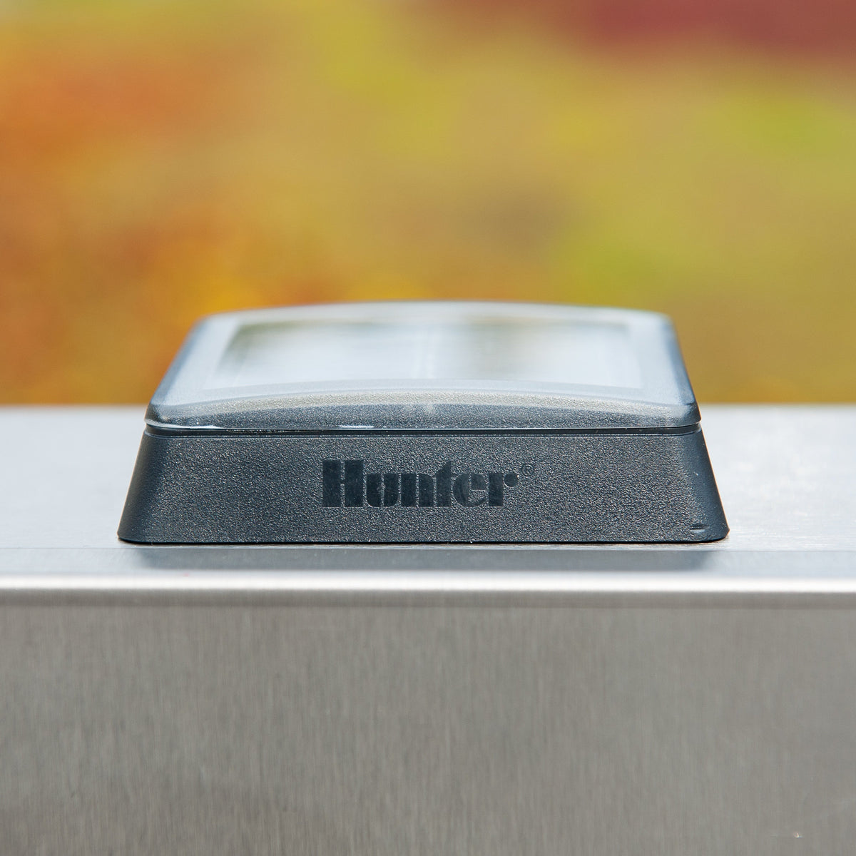Metallic object with 'Hunter' branding on a blurred natural background