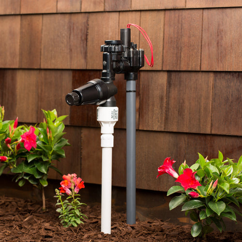 Garden irrigation system with flowers and wooden wall in the background