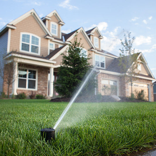 Sprinkler watering grass in front of a house