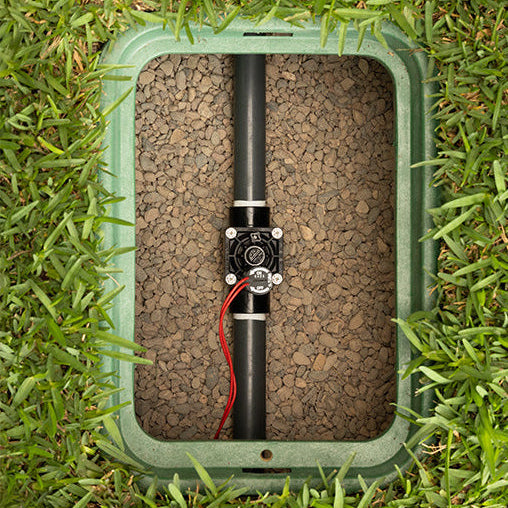 Underground sprinkler system valve box with pipe and valve on grass
